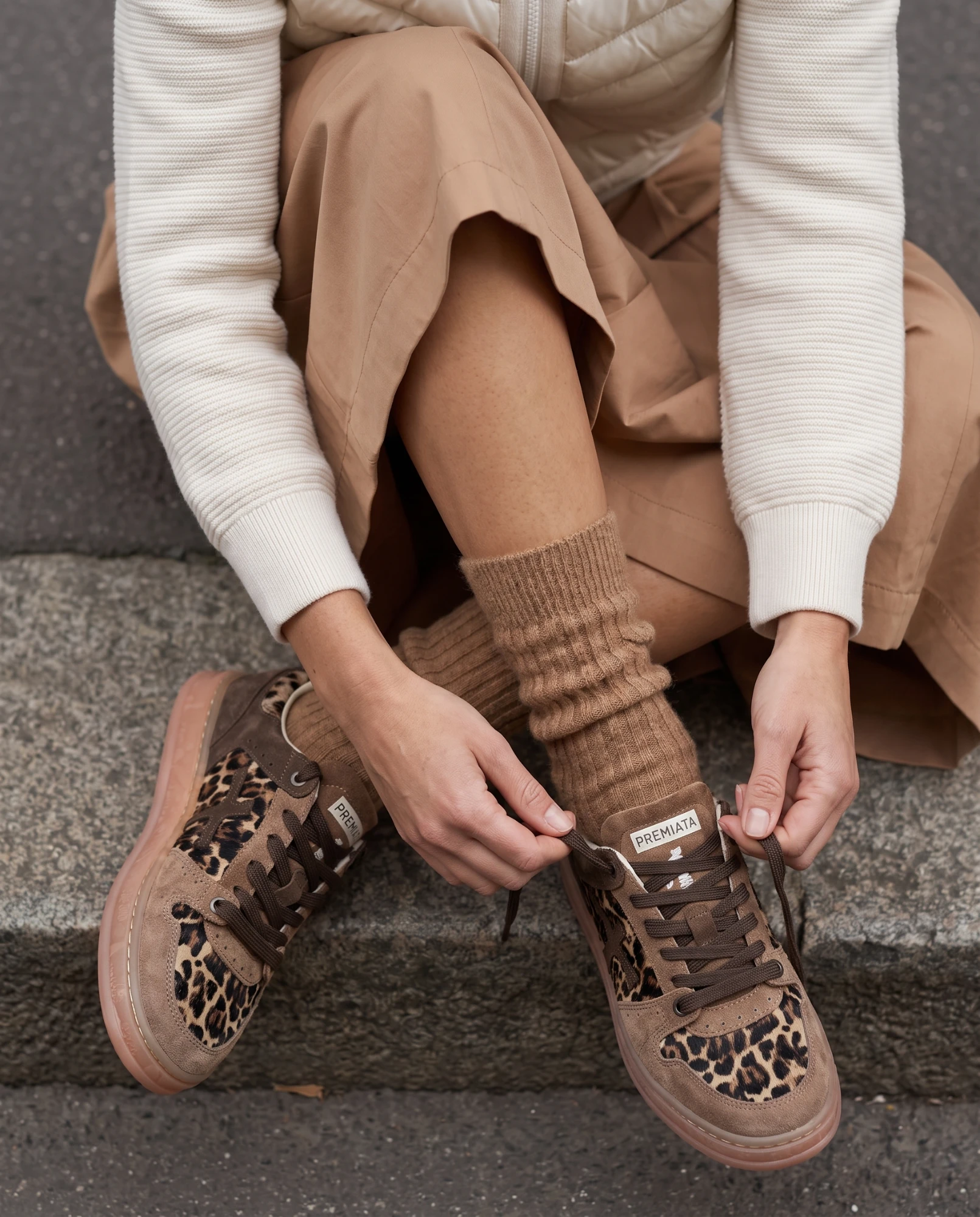 Detalle de zapatillas de ante con estampado de leopardo y calcetín de canalé camel